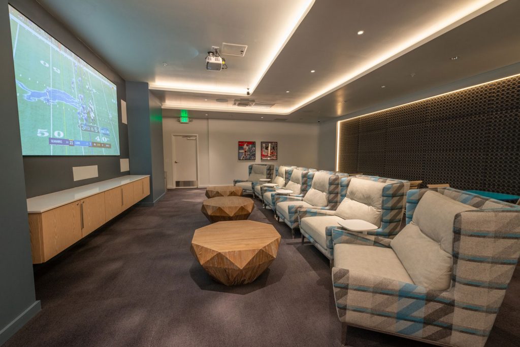 Theater room with large TV, carpet flooring, and chair seating