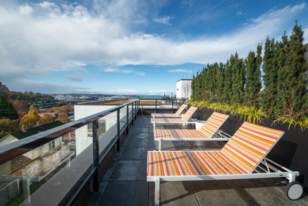 Outdoor rooftop deck with sun tanning beds, garden, and views overlooking city