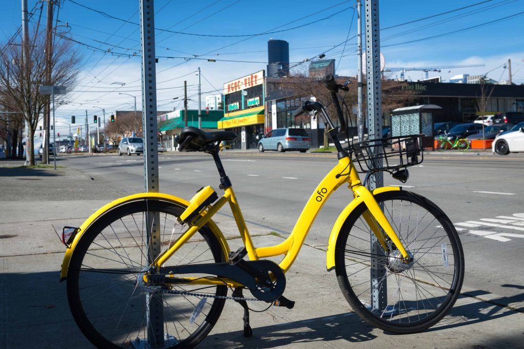 Yellow bicycle chained to post alongside street