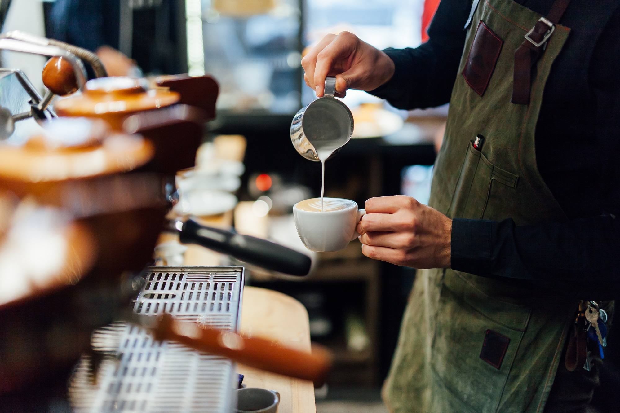Man pouring a cup of coffee behind bar at a coffee shop