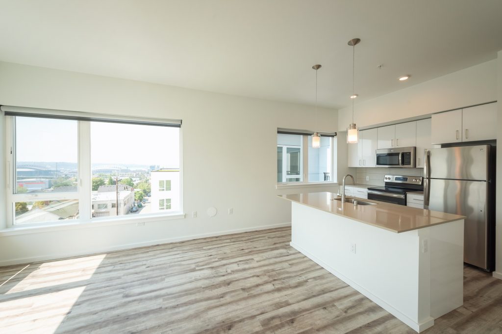 Empty living room with wood-style flooring and open access to the kitchen